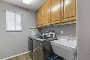 Laundry room featuring separate washer and dryer, cabinet space, and wood finished floors