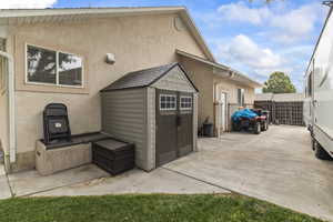 Rear view of property featuring a patio, a storage unit, and stucco siding