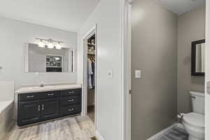 Full bath with vanity, wood finished floors, a garden tub, and a spacious closet