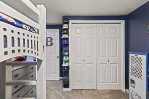 Carpeted bedroom with a closet and a textured ceiling