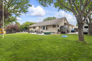 Rear view of property featuring a storage unit, stucco siding, a patio area, a playground, and roof with shingles