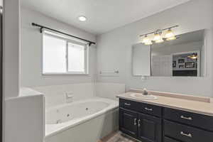 Full bathroom with vanity, a whirlpool tub, and wood finished floors