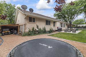 Back of house with an outdoor hangout area, stucco siding, and a trampoline