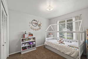 Carpeted bedroom with a closet and baseboards