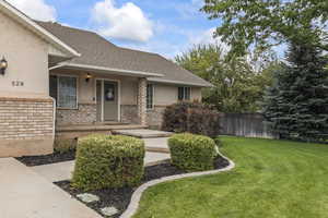 Property entrance with stucco siding, brick siding, roof with shingles, and covered porch