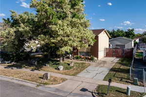 View of front of house featuring a gate, concrete driveway, a storage building, and brick siding