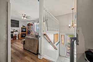 Living room featuring plenty of natural light, wood finished floors, ceiling fan, a chandelier, and a textured ceiling