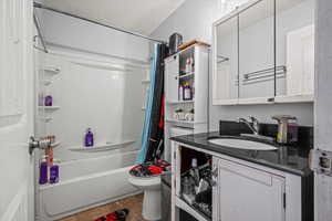 Bathroom with vanity, shower / bathtub combination with curtain, and a textured ceiling