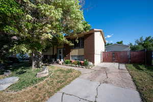 View of front of home with brick siding, a gate, and asphalt driveway