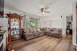 Living area with a ceiling fan, a textured ceiling, and light wood finished floors