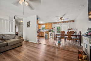 Living room featuring a ceiling fan, a textured ceiling, and light wood finished floors