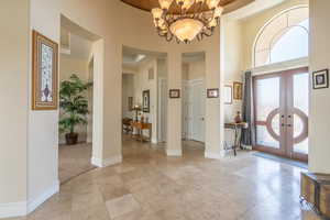 Foyer entrance with a towering ceiling, a chandelier, and french doors