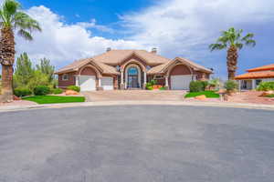 Mediterranean / spanish-style home featuring stucco siding, a tile roof, a garage, a chimney, and driveway