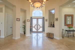 Entryway with a high ceiling, french doors, a chandelier, and light tile patterned floors