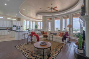 Living area with a raised ceiling, a ceiling fan, recessed lighting, light wood finished floors, and healthy amount of natural light