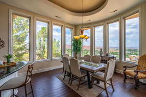 Dining area with dark wood-style flooring and a raised ceiling