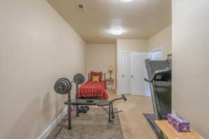 Workout area featuring a textured ceiling and carpet floors