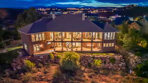 Back of house at night with a balcony, a chimney, and a patio area