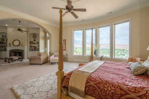 Bedroom with ornamental molding, multiple windows, light carpet, arched walkways, and a high end fireplace
