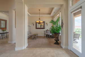 Entrance foyer featuring a chandelier, light carpet, a tray ceiling, and light tile patterned floors