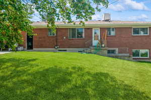 Back of house with a yard and brick siding