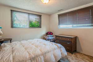Bedroom with light carpet and a textured ceiling