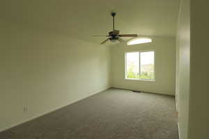 Unfurnished room featuring a ceiling fan, carpet, and lofted ceiling