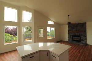 Kitchen featuring dark wood finished floors, white cabinetry, light stone counters, a fireplace, and high vaulted ceiling