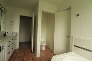 Bathroom with double vanity, a garden tub, and tile patterned flooring