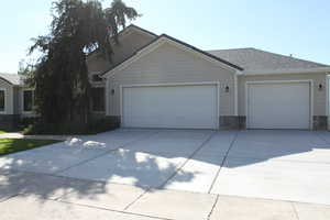View of front facade featuring driveway, a garage, stone siding, and roof with shingles