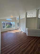 Unfurnished living room featuring dark wood-style flooring and baseboards