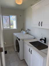 Laundry area featuring cabinet space, washing machine and clothes dryer, and light tile patterned floors