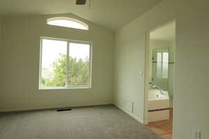 Empty room featuring vaulted ceiling, ceiling fan, tile patterned floors, and carpet