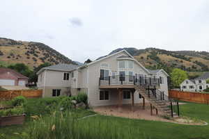 Rear view of property with stairway, a deck with mountain view, and a patio