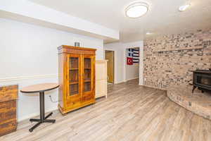 Basement featuring a wood stove, stairway, a textured ceiling, and LVP floors
