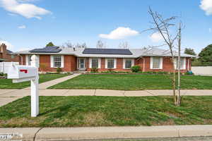 Ranch-style brick house featuring solar panels and a large yard