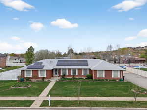 View of front of house with solar panels, brick siding, and a shingled roof