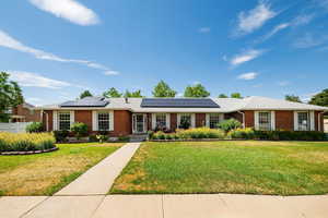 Ranch-style house featuring brick siding and fully-owned roof mounted solar panels