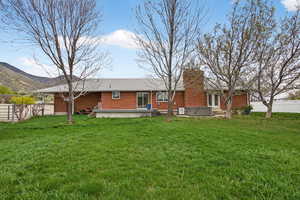Rear view of property featuring a hot tub, brick siding, a chimney, and a mountain view