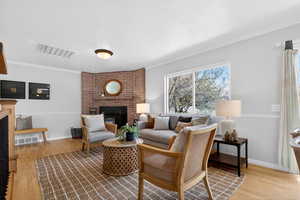 Living room featuring a wood-burning fireplace and wood floors.