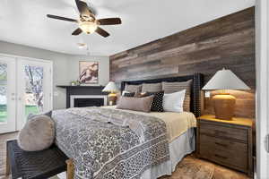 Primary bedroom with a fireplace, wood accent wall, brand new carpet, and French door access to hot tub.