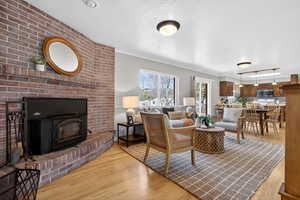 Open layout living room featuring a wood-burning fireplace and wood floors.