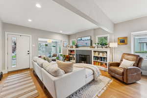 Living room with light wood-type flooring, recessed lighting, and a brick fireplace