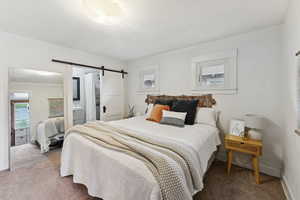 Carpeted bedroom featuring a barn door and ensuite bath