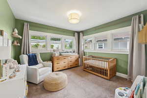 Carpeted bedroom featuring a nursery area