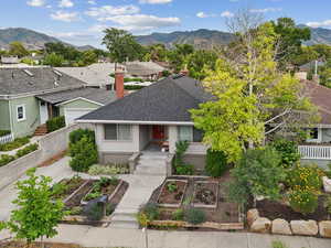 View of front facade with a vegetable garden, a shingled roof, a mountain view, and a chimney