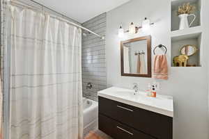 Bathroom featuring vanity and shower / bathtub combination with curtain