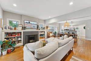 Living room with light wood-style flooring, a brick fireplace, and recessed lighting
