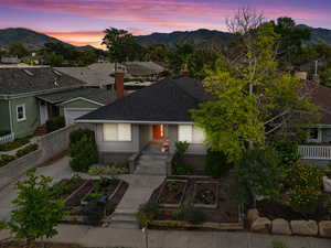 View of front of home featuring a garden, a mountain view, a shingled roof, and a chimney
