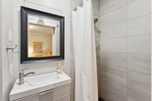 Bathroom featuring tiled shower and vanity